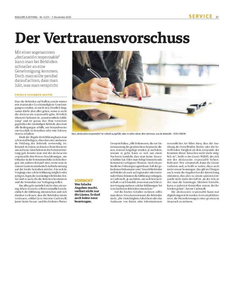 Zeitungsartikel mit Foto auf der eine Hand mit Stift schreibt