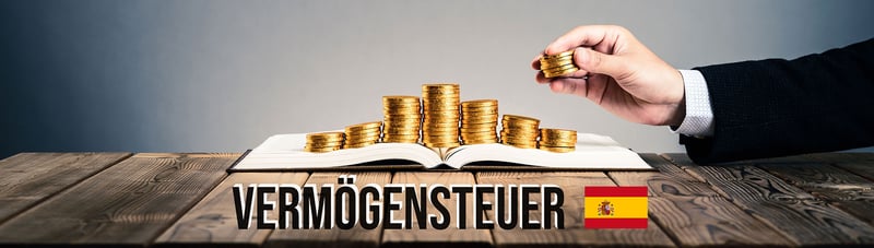 Bild von einem Holztisch auf dem ein geöffnetes Buch liegt. Auf diesem Buch liegen Geld-Münzen und eine Hand legt weitere dort drauf. Unten kann man den Schriftzug Vermögensteuer und einer spanischen Flagge daneben.